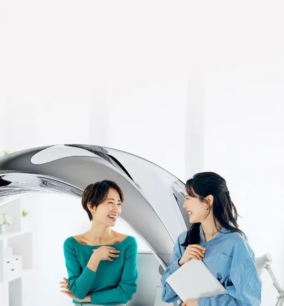 Two smiling professional women converse in a bright office.