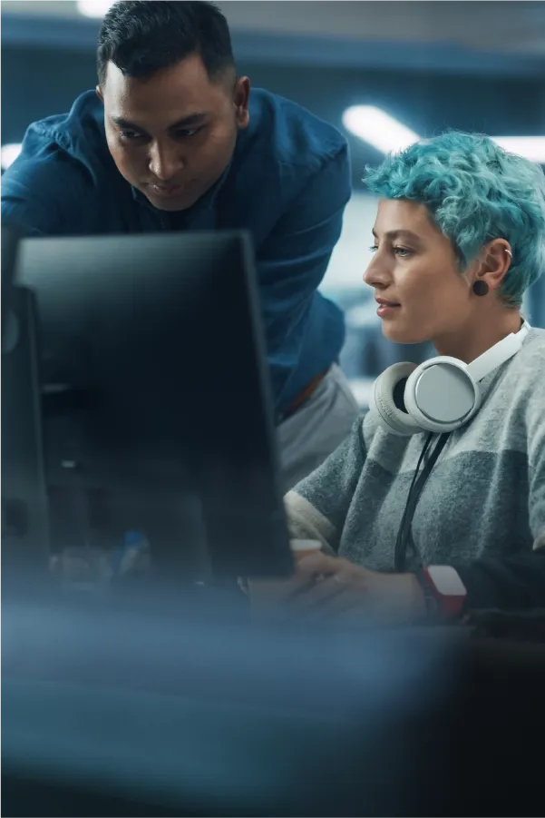 Two IT professionals collaborating while reviewing code on a computer screen.