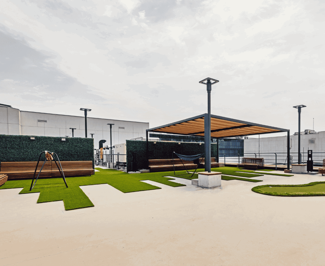 ჭერის ტერასა ხის პერგოლით, ხელოვნური ბალახით, ჰამაკებით და სკამებით ღია ურბანულ სივრცეში.