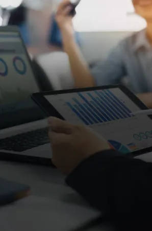 Business professionals reviewing data charts on a tablet during a collaborative meeting.