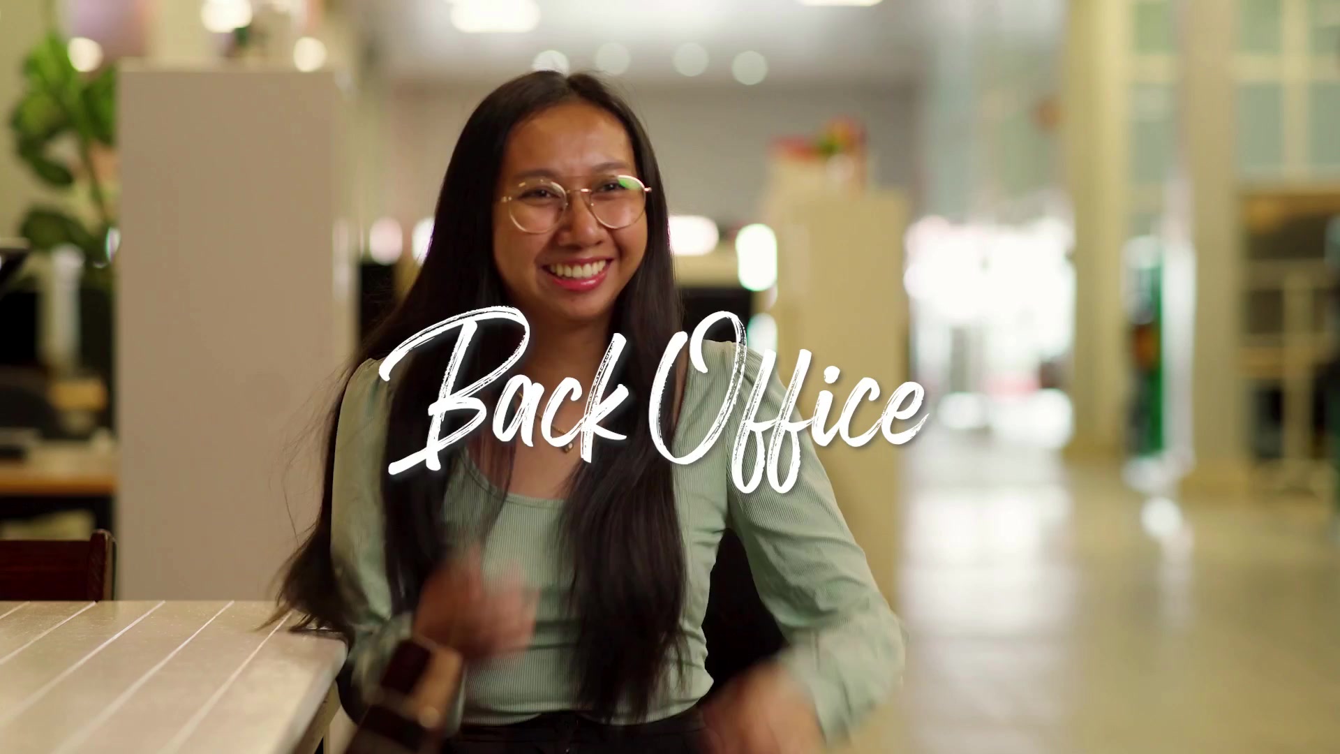 Smiling woman in office with text overlay Back Office