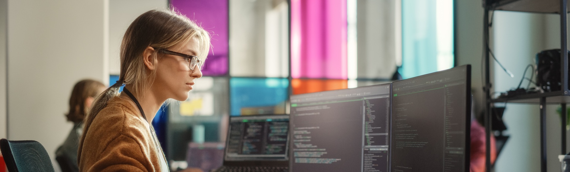 Focused woman programmer coding at her computer in a professional setting.