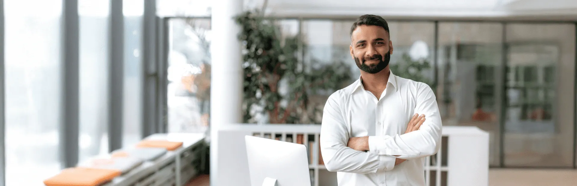 Confident businessman smiling with arms crossed in a modern office setting