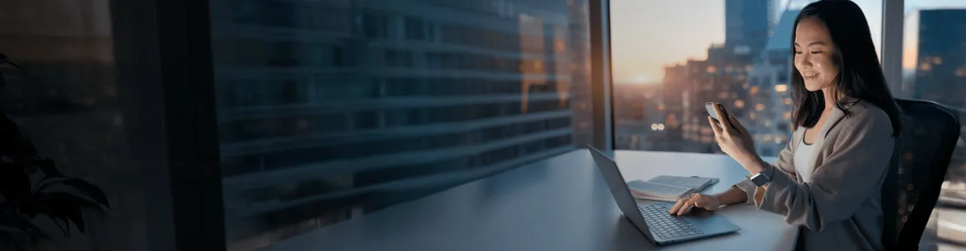 Woman working on a notebook and looking to a cellphone.