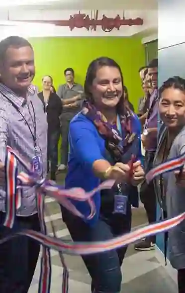 Celebrating the opening of a building with 3 people, cutting the ribbon to indicate something has newly opened
