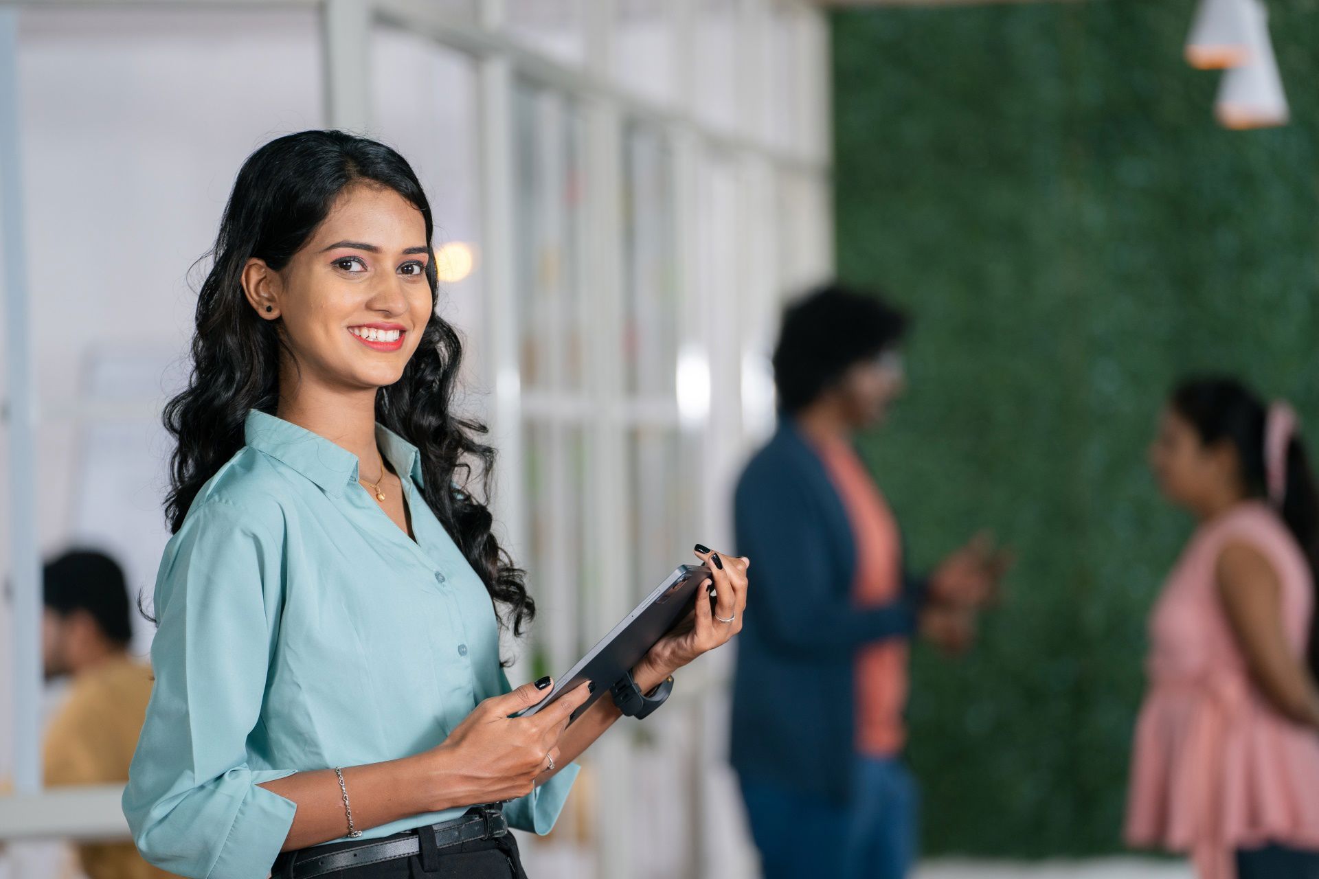 A young business woman holding a tablet inside a modern and green office A young business woman holding a tablet inside a modern and green office