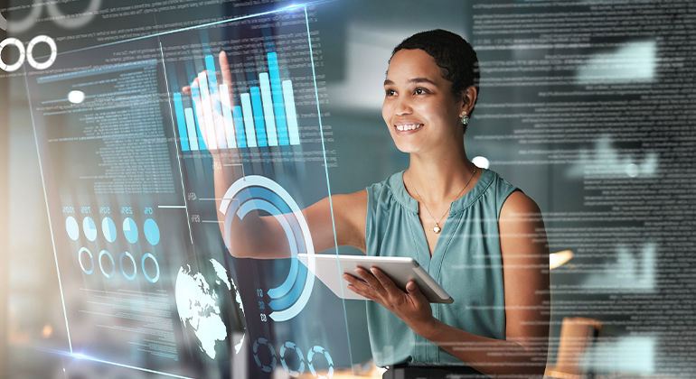 Person interacting with a large transparent digital interface displaying charts, graphs, and data analytics while holding a tablet.