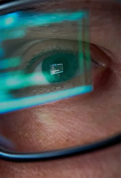 Close up of a programmer’s eyes with code reflected in glasses.