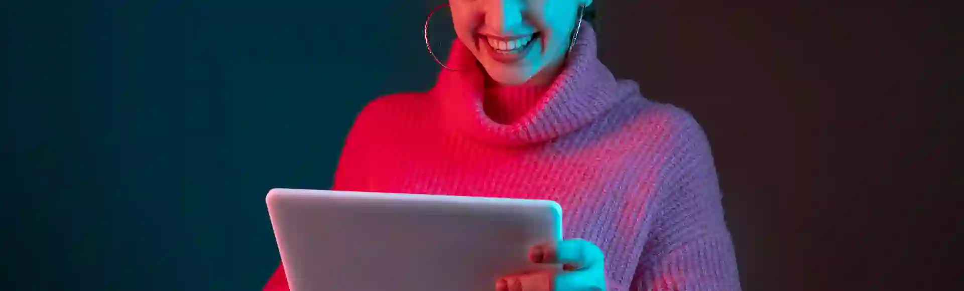 Smiling girl in a pink blouse reading blog articles on her tablet.