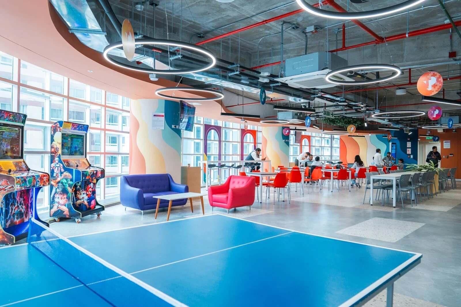 Colorful break area with arcade games, seating, and a ping-pong table.