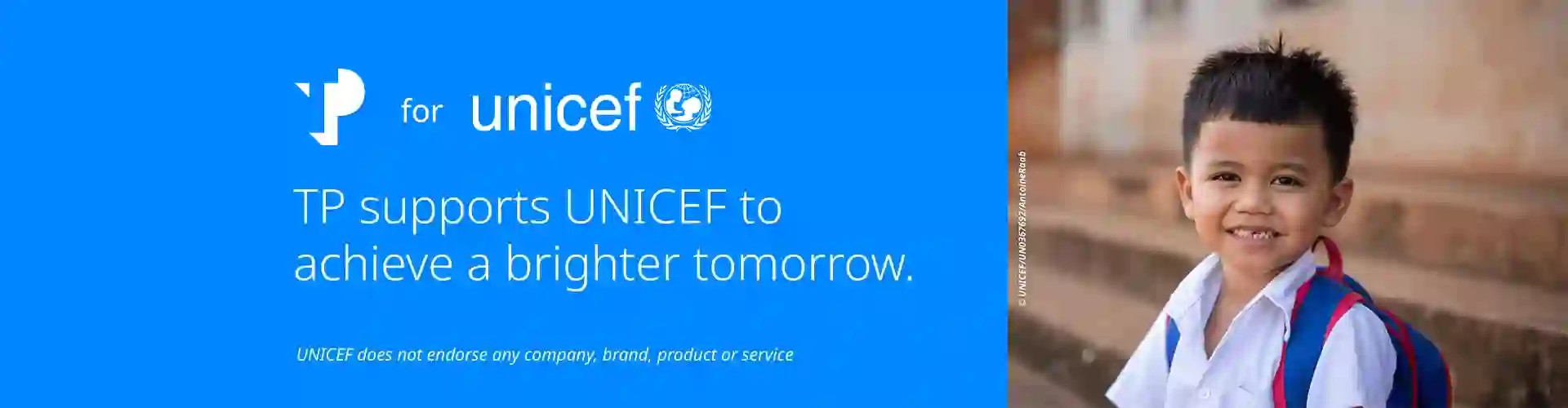 Smiling young boy wearing a backpack, next to a blue UNICEF banner with TP logo and the message supporting a brighter tomorrow.