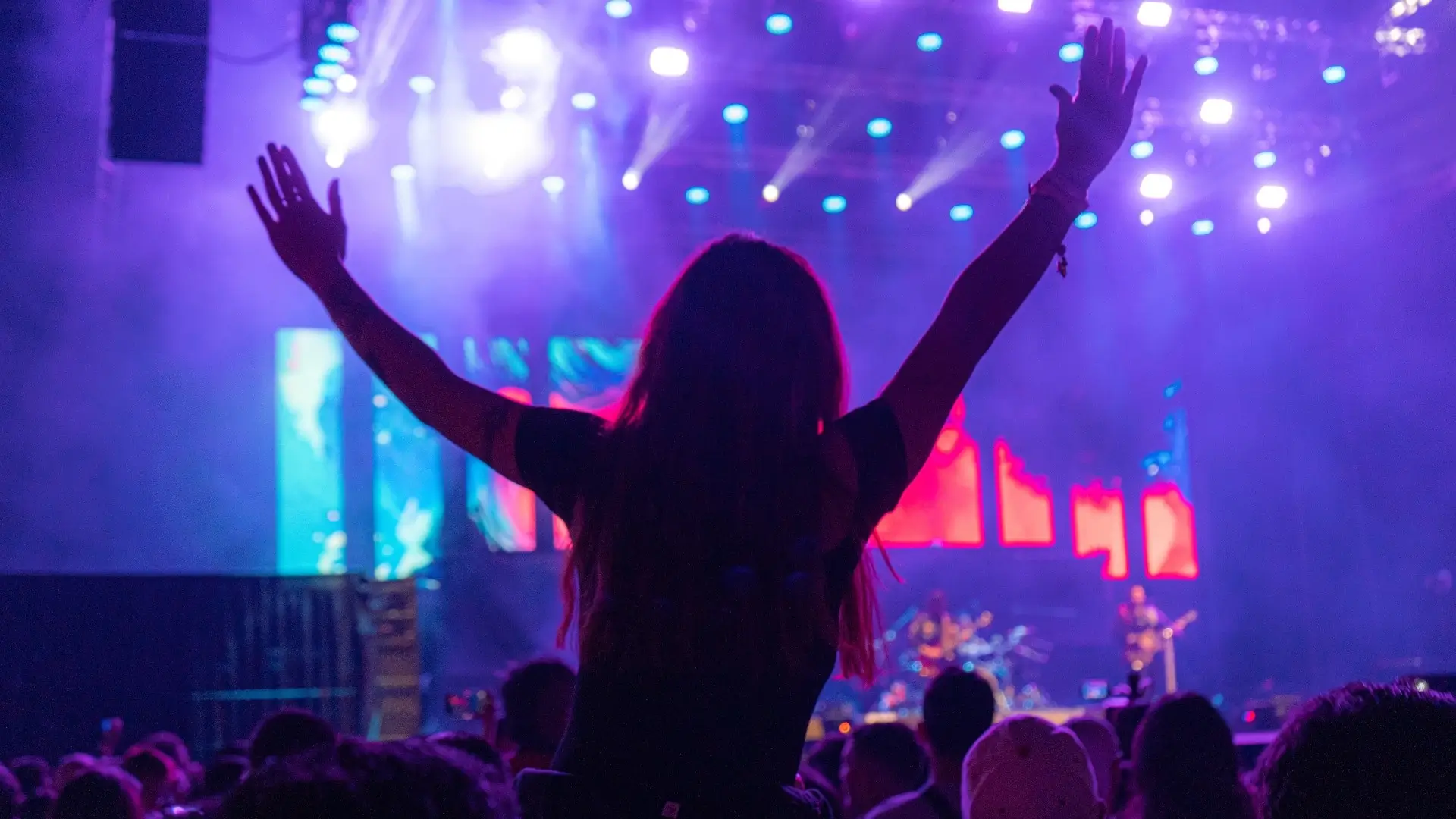 Woman in front of a music stage with her hands up.