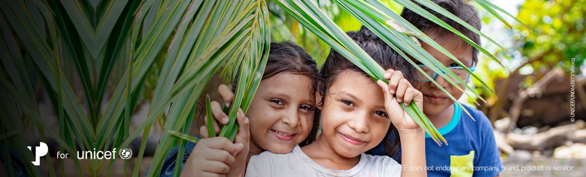 Smiling children behind palm leaves, symbolizing protection in TP for UNICEF programs.