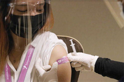 TP employee receiving a vaccination shot with a TP badge on their arm.