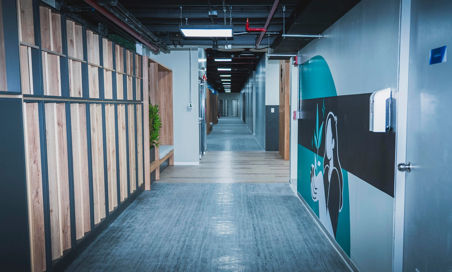 Modern hallway with wood panels, seating areas, and a wall mural in a TP office space.