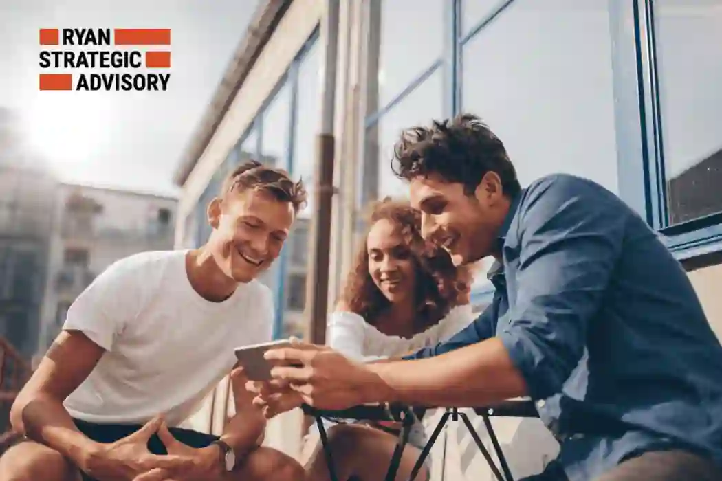 Three people are gathered outdoors, smiling while looking at a smartphone. 