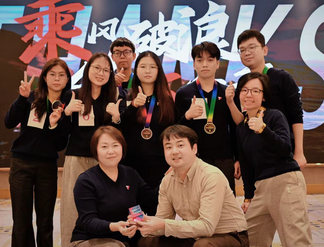 TP team celebrates their victory with medals, posing proudly at the award ceremony.