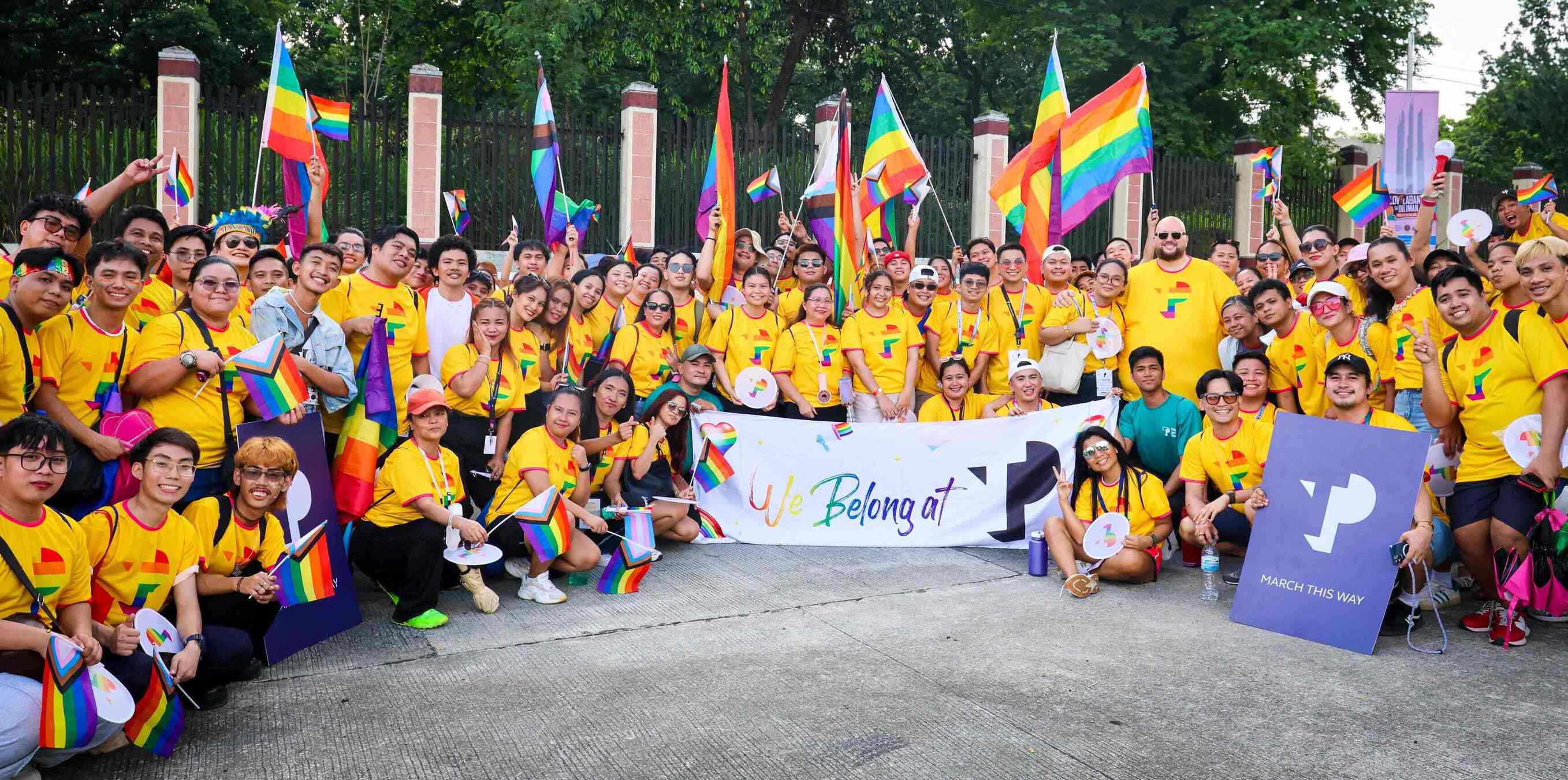 Large group of TP employees posing with rainbow flags at Pride event