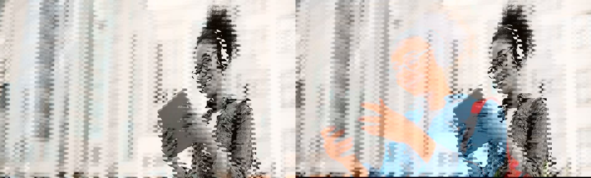 Giovane donna afrodiscendente sorridente ascolta musica all’aperto con un headset.