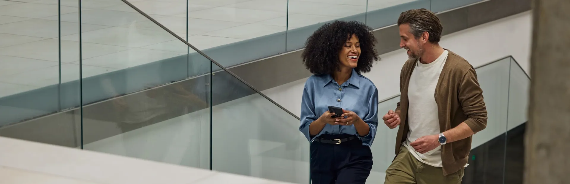 Business couple walking up the stairs together in a modern office.