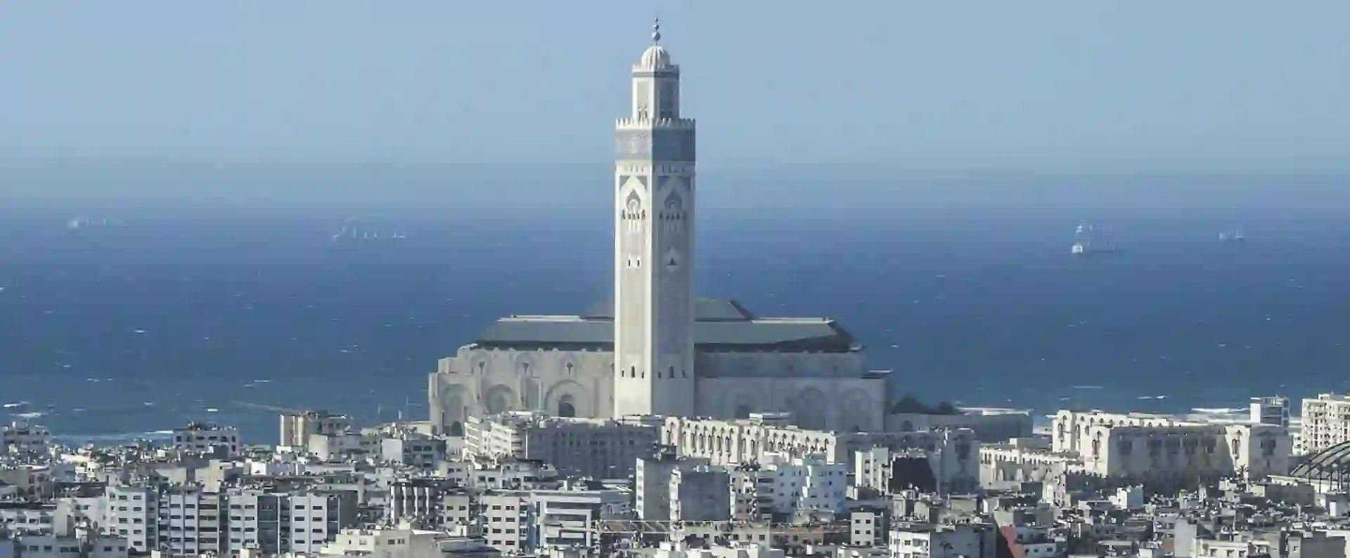 Aerial view of a Moroccan city with intricate architecture, narrow streets, and a beautiful blue ocean in the background.