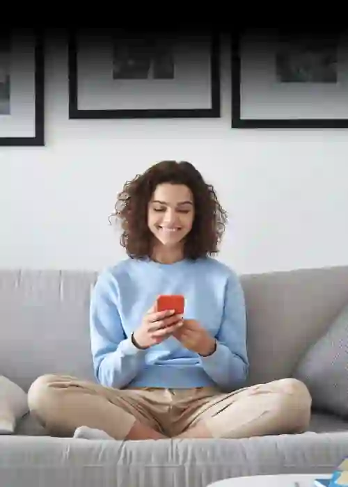 Evinde kanepede oturup akıllı telefonunu kullanan genç kadın, TP’nin dijital çözümlerini temsil ediyor.