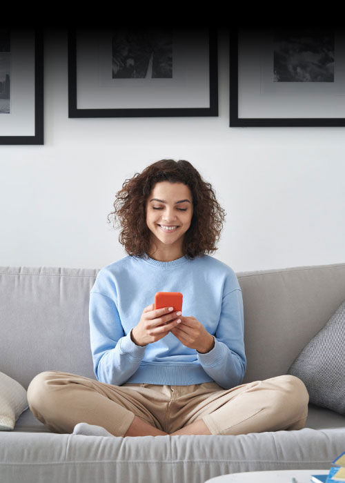 Evinde kanepede oturup akıllı telefonunu kullanan genç kadın, TP’nin dijital çözümlerini temsil ediyor.