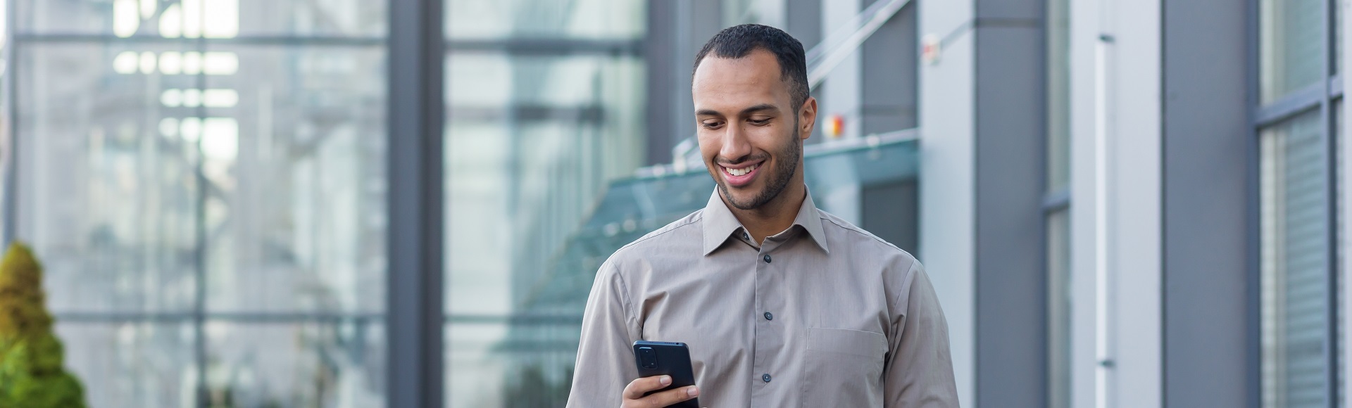 Smiling professional using a smartphone, representing digital engagement and connectivity.