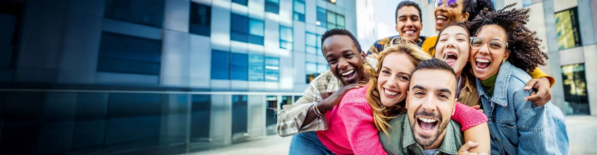 Group of smiling friends taking a picture outside of a modern office building