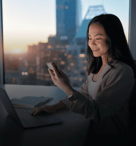 Woman working on a notebook and looking to a cellphone.