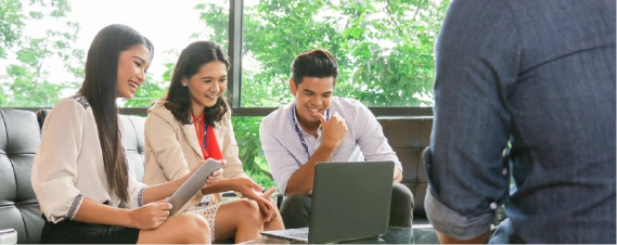 Colleagues collaborating around a laptop during a team meeting in a bright office.