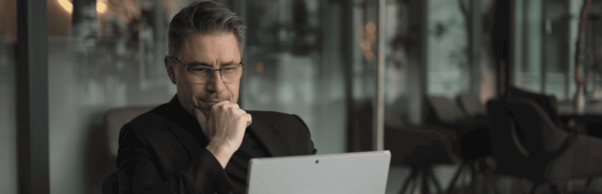 Thoughtful man with hand on chin while working on computer