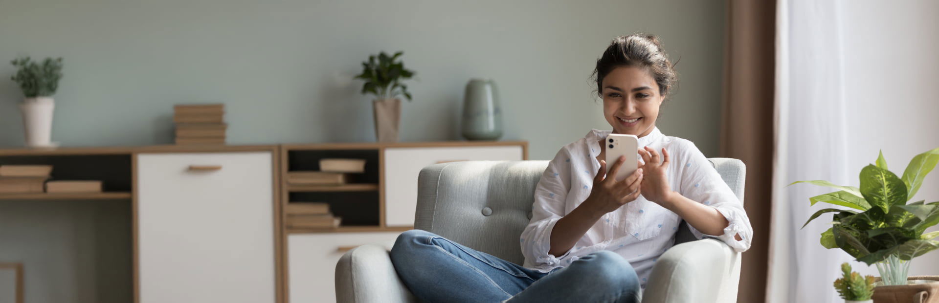Woman comfortably sit on her living room while browsing smartphone