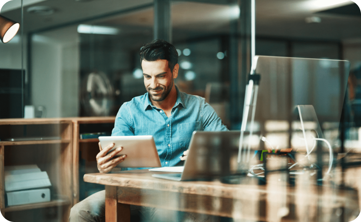 Man sitting at a desk in a modern office while browsing his tablet