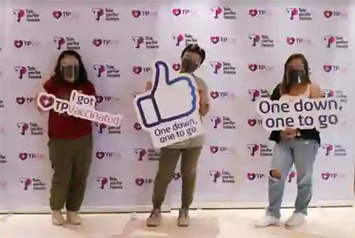 TP employees pose with vaccination signs at a TPVac event.