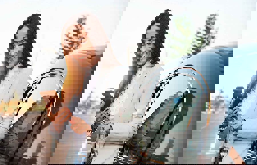 Smiling woman by her car checking her phone, illustrating TP Reach transforming Volkswagen service.