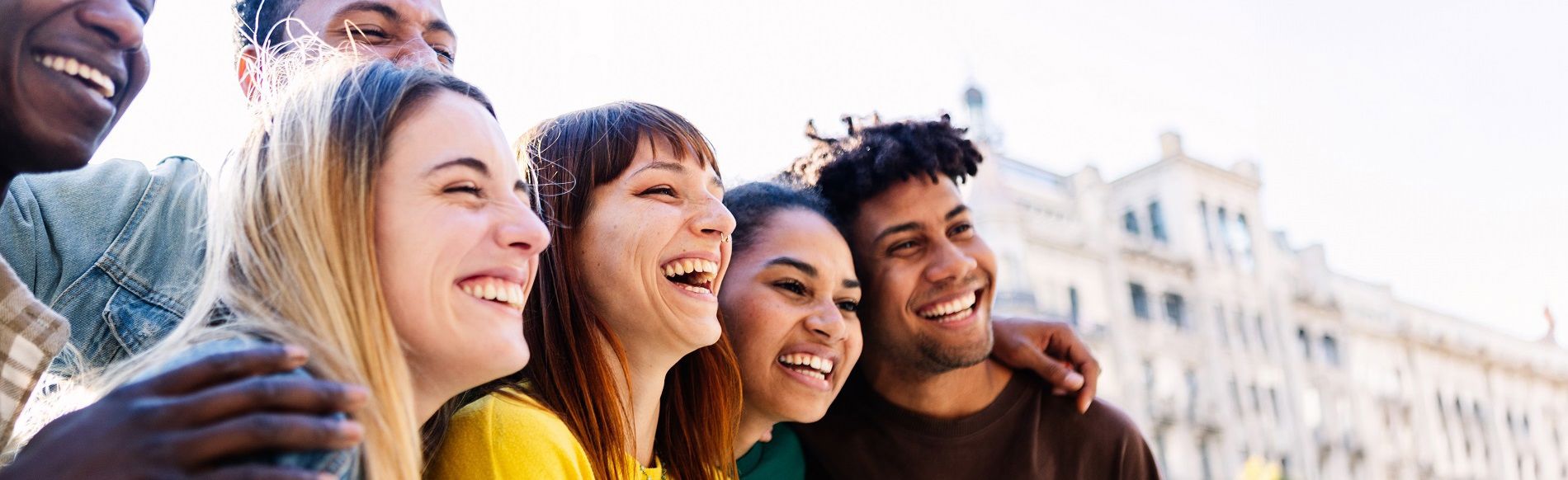A diverse group of three men and three women smiling and taking a photo outdoors on a sunny day.