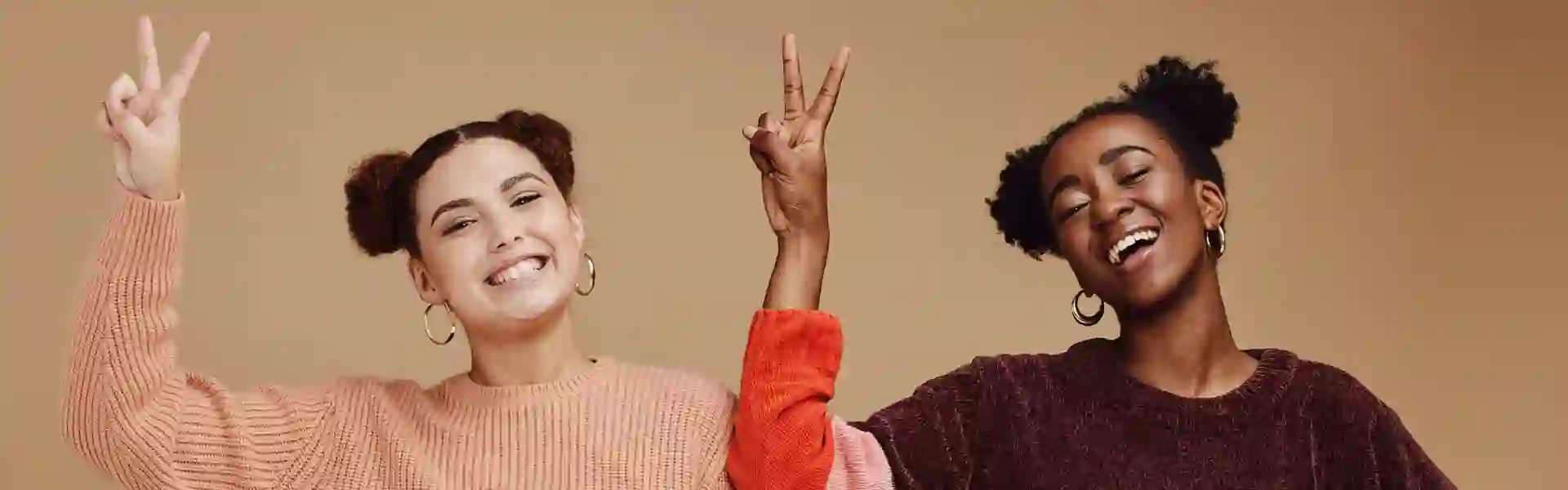 Two cheerful girls smiling and gesturing with their hands towards the camera