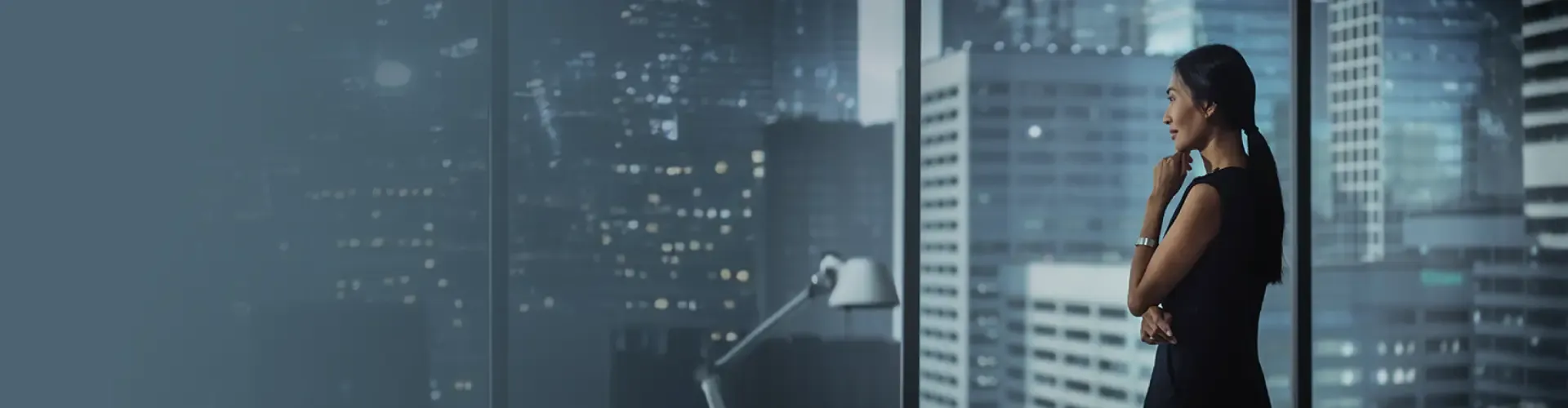 Thoughtful Asian businesswoman looking out the window of her modern office.