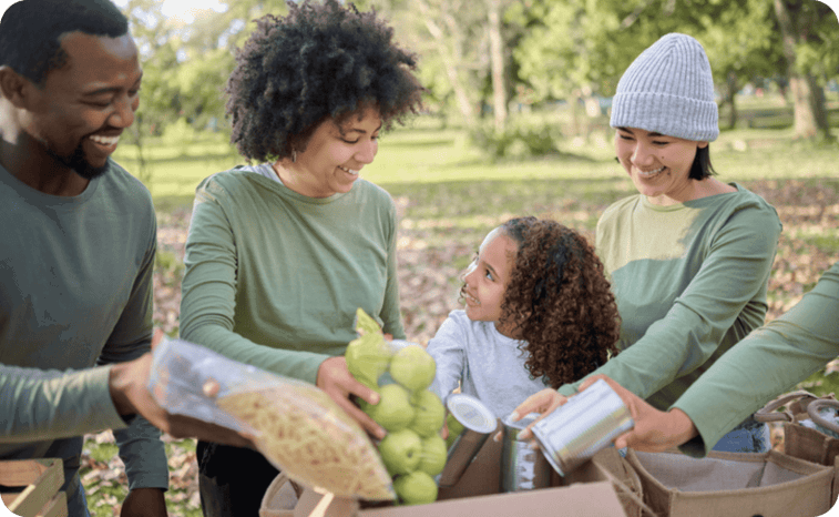 A group of four people and a child sorting food items into boxes outdoors.