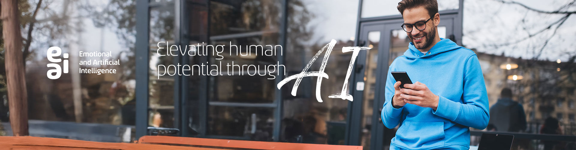 Smiling young man on the balcony of an office browsing his cell phone