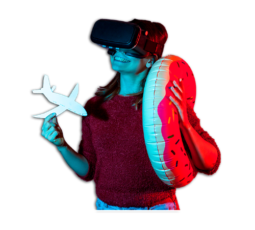 Person wearing VR headset holding a toy plane and inflatable, under blue and red lights.