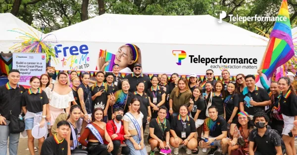 TP employees celebrating diversity and inclusion at Pride event with rainbow flags and Free to Be Me banner
